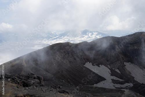 Severe mountain landscape. The rim of a volcanic crater. Low clouds. Travel and hiking on the Kamchatka Peninsula. Nature of Siberia and the Russian Far East. Gorely volcano, Kamchatka Krai, Russia. photo
