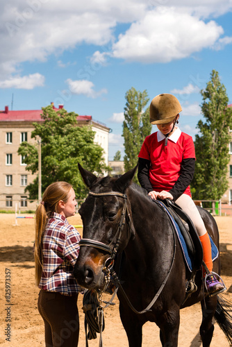 Instructor adjusts young rider's position in equestrian training.