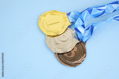 Gold, silver and bronze medals with blue ribbons on blue background.