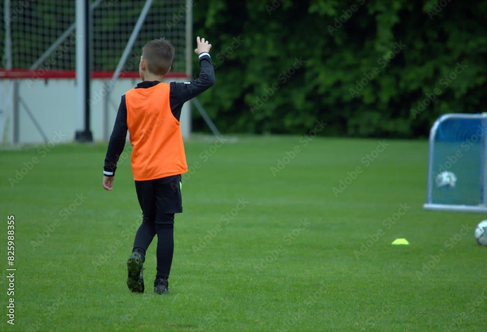 Obraz premium Boy in an orange T -shirt on a football field