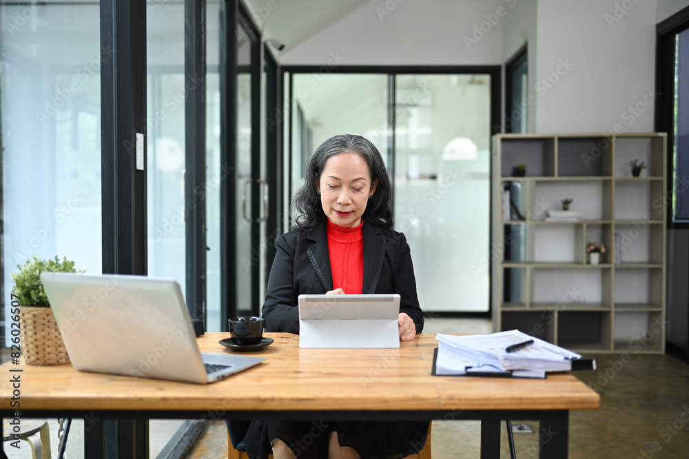 Portrait of elegant mature businesswoman using digital tablet at her workplace Portrait of elegant mature businesswoman using digital tablet at her workplace