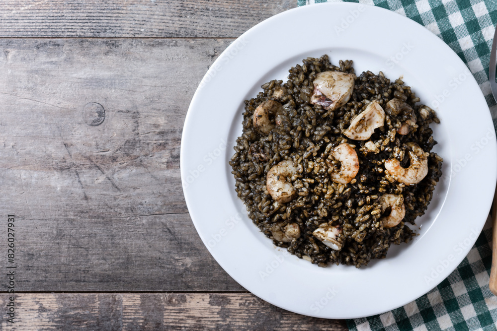 Black rice with seafood on wooden table. Top view. Copy space Black rice with seafood on wooden table. Top view. Copy space