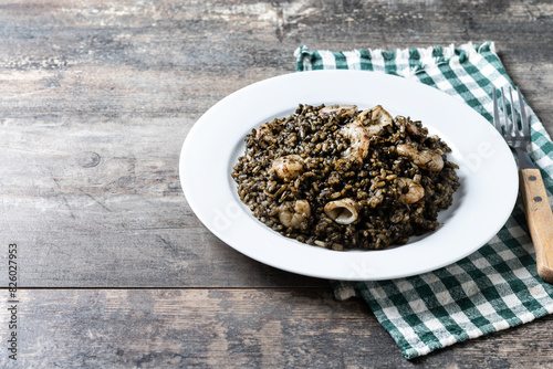 Black rice with seafood on wooden table. Copy space photo