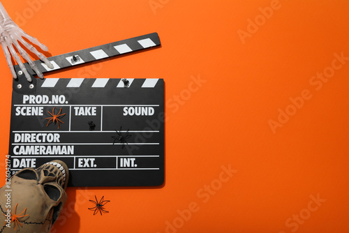 Clapperboard and Halloween decorations on orange background, space for text photo