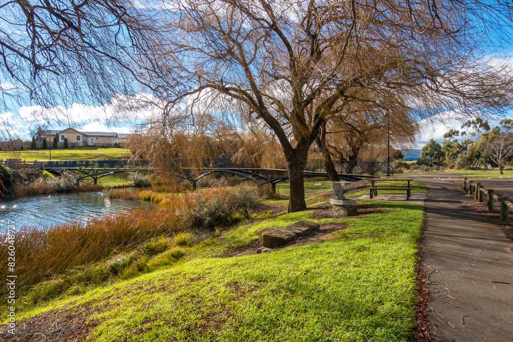 Beautiful scenery at the Riverbank of Elizabeth River with autumn trees and a footbridge in the distance, Campbell Town. Tasmania, Australia Beautiful scenery at the Riverbank of Elizabeth River with autumn trees and a footbridge in the distance, Campbell Town. Tasmania, Australia