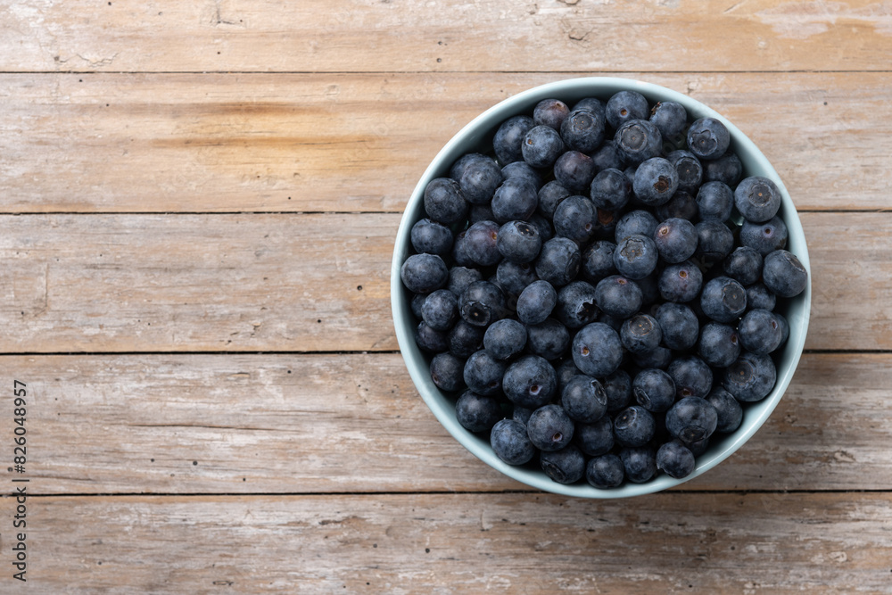 Blueberries in green bowl on wooden table. Top view. Copy space Blueberries in green bowl on wooden table. Top view. Copy space