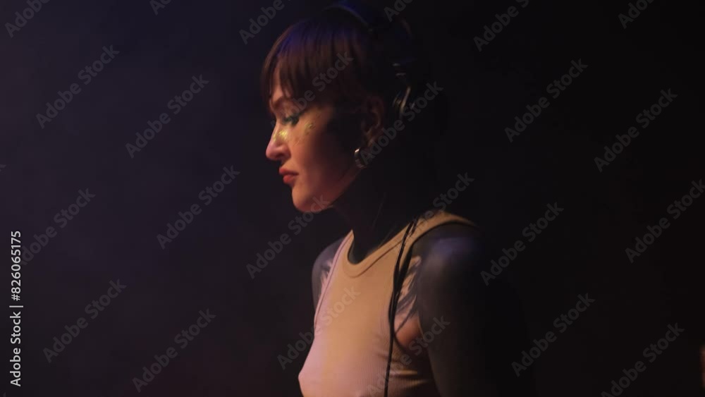 Caucasian girl DJ playing electronic music in a nightclub. Side view Caucasian girl DJ playing electronic music in a nightclub. Side view