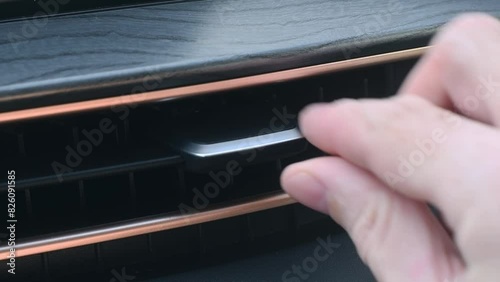 A person adjusts the flow of cold or hot air using an air deflector in the interior of a car. photo