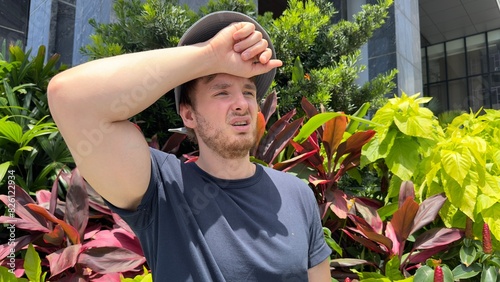 Fotografie Young tired exhausted man suffering from heat, high temperature in the tropical city
