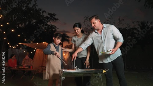 Family together camp in garden, Mom dad and daughter grill food for family member. Outdoor camping activity to relax with nature and spend time with young generation cross generation gap. Divergence. photo