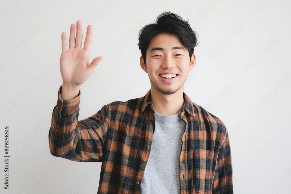 Friendly Asian Man Smiling and Waving Hand Wearing Checkered Shirt in Studio Portrait Friendly Asian Man Smiling and Waving Hand Wearing Checkered Shirt in Studio Portrait