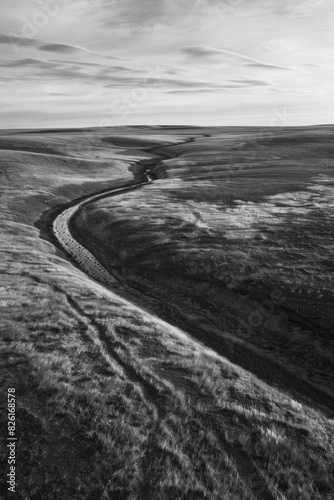 Aerial view of a monochrome tundra landscape, capturing the subtle textures and patterns created by the sparse vegetation and undulating terrain. 