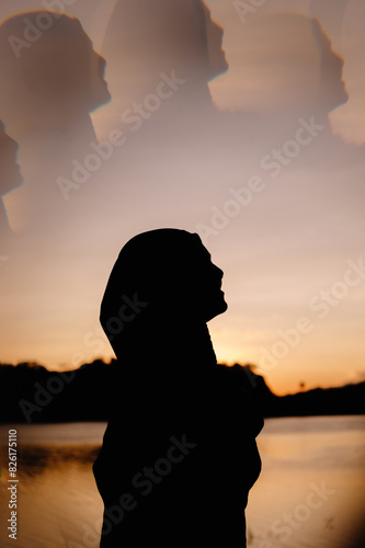 Silhouette of a happy Asian Muslim woman wearing a hijab at sunrise with a light flare effect from a crystal ring that reflects light and images