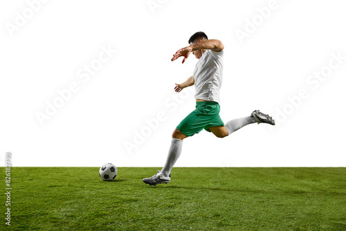Dynamic image of young footballer prepares to strike soccer ball on lush green pitch against white studio background. Concept of professionals sport, competition, tournament, energy, action. Ad