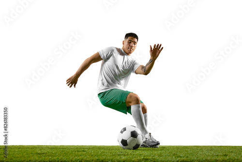 Young athletic man training dribbling technique in motion on green lash field against white studio background. Concept of professionals sport, competition, tournament, energy, action. Ad