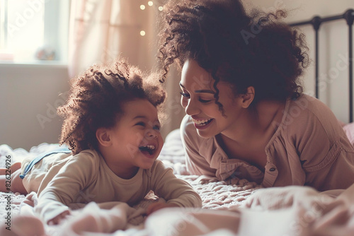 A woman and a child are laying on a bed, smiling and laughing photo