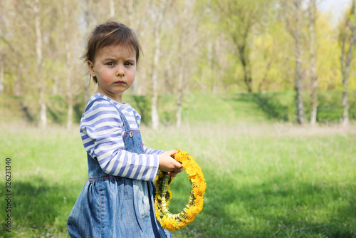 Little adorable smiling girl with dandelions in spring outdoors.