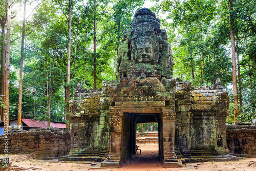 Gateway to ancient Ta Som temple in Cambodia. Gopura with stone face on woods background. photo