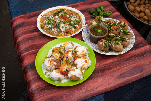 Spicy Chotpoti, plain or Doi Fuchka, pan puri, or gol gappa filled with herbs with spicy water served in plate isolated on wooden table side view of bangladeshi street food