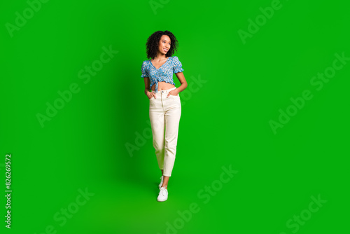 Full length portrait of pretty young girl walk look empty space wear top isolated on green color background
