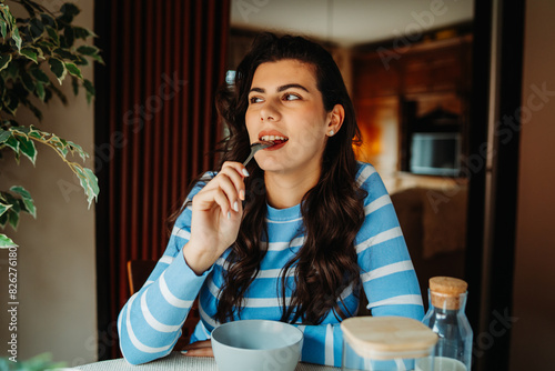 Obraz na płótnie One young caucasian woman is eating corn flex breakfast at home before work