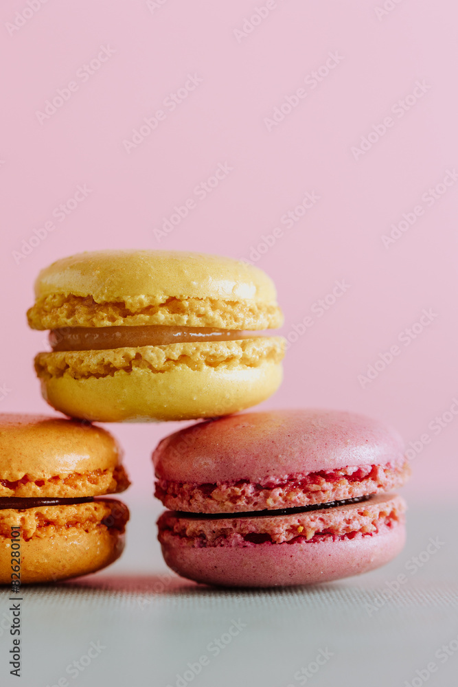 Colorful macarons stacked against a pink backdrop
