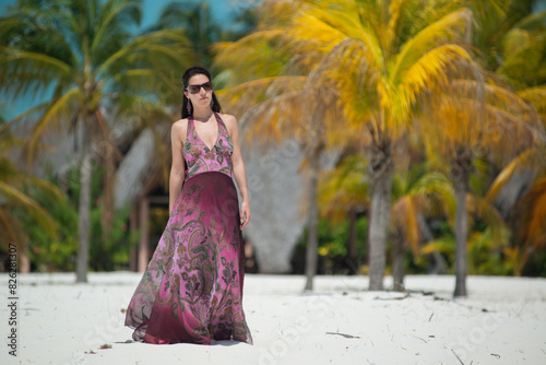 a girl in a dress and hat walks along the white sand among palm trees, dance siren in Cuba, Caribbean sea, palm trees on the beach photo