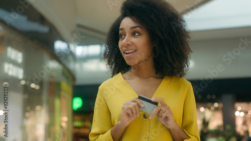 Joyful delighted excited woman walking shopping mall boutique buy bank card spend money finance black friday discount payment sale fashionable trendy store exclusive purchase price multiracial brand