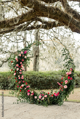 Circular floral arrangement with pink and red flowers under a tree