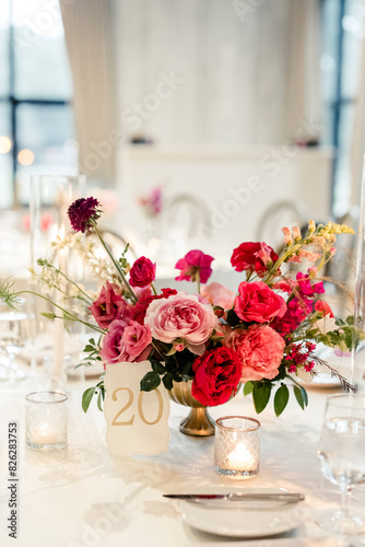 Table centerpiece with pink and red flowers, candles, and table number