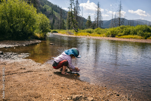 Child playing near a river in a scenic mountain landscape