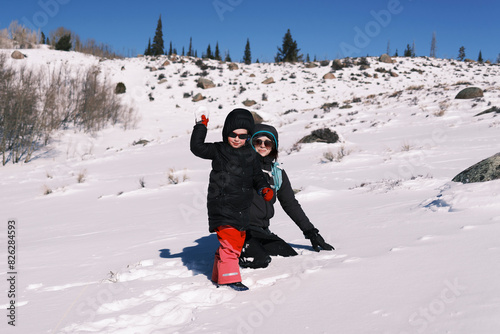 Mother and child playing in snowy landscape with mountains in ba