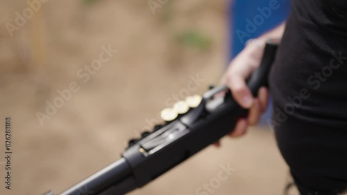 Guy with shotgun reload new shotshells into barrel chamber, shooting range photo
