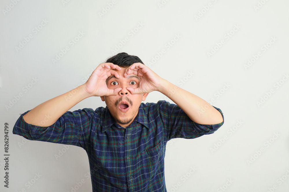 portrait of excited Asian man shocked gesture with both hands pretending to wear glasses portrait of excited Asian man shocked gesture with both hands pretending to wear glasses