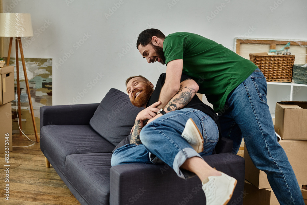 gay couple lays on a couch in a moment of fun and relaxation, amidst boxes in a new home. gay couple lays on a couch in a moment of fun and relaxation, amidst boxes in a new home.