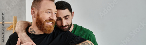 A bearded man warmly embraces his partner