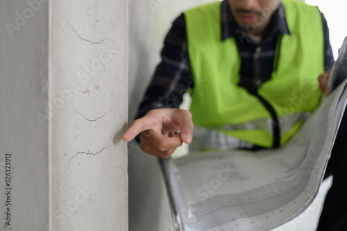 Male civil engineer with inspection check sheet consult with construction site foreman technician for inspect building condition defect pointing wall crack wait for repair.