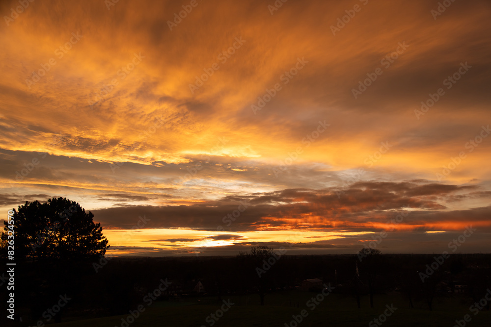 the sun setting over an open field with houses and trees the sun setting over an open field with houses and trees