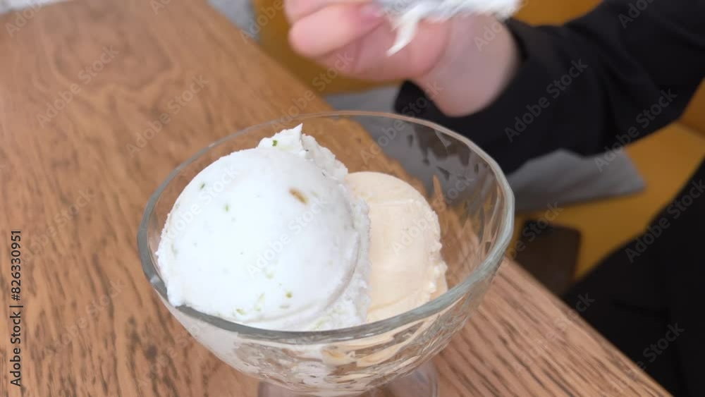 Ice cream in glass Cup on the table rotates on a black background. Wooden table. Eating vanilla ice cream. Ice cream in a glass bowl Ice cream in glass Cup on the table rotates on a black background. Wooden table. Eating vanilla ice cream. Ice cream in a glass bowl