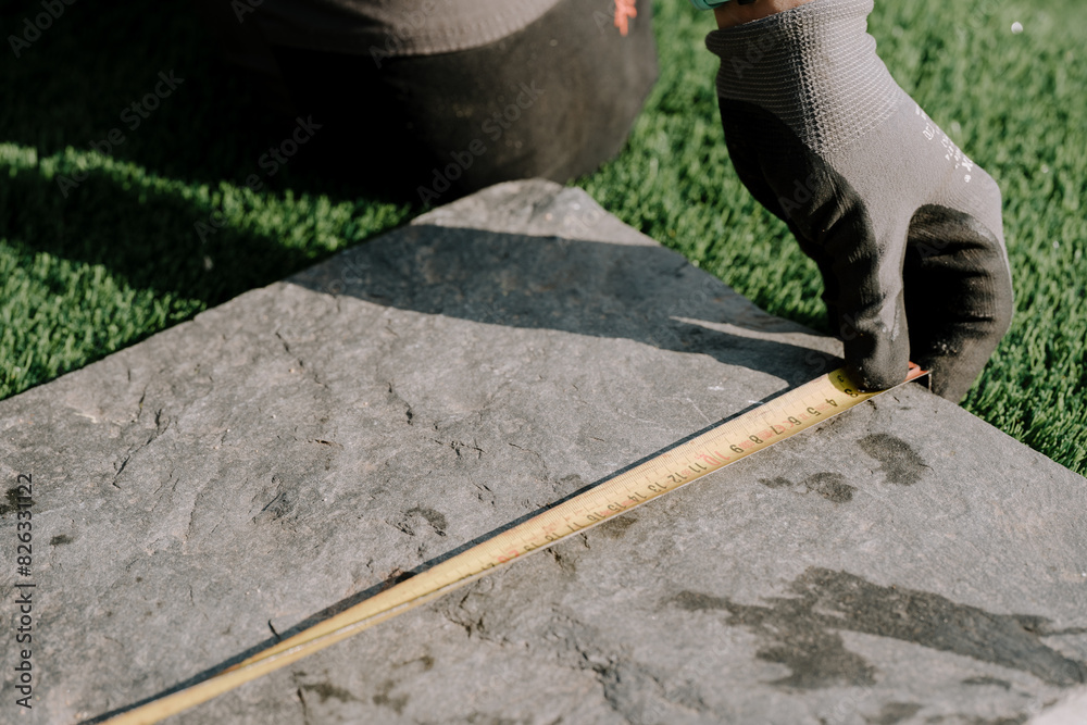 Man measuring the length of a rock on the ground Man measuring the length of a rock on the ground