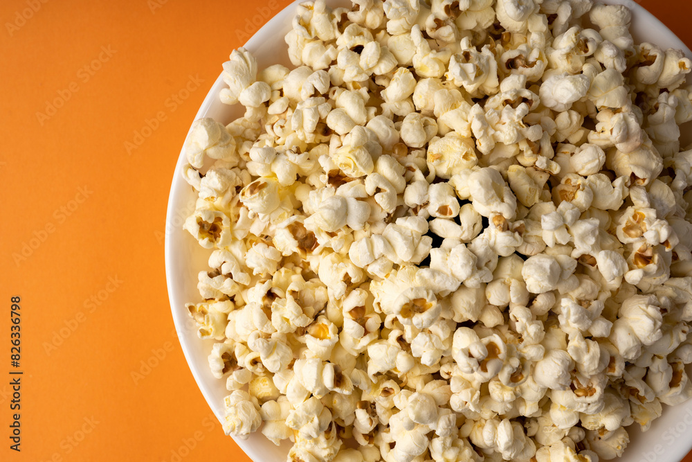 White bowl of popcorn on an orange table. White bowl of popcorn on an orange table.