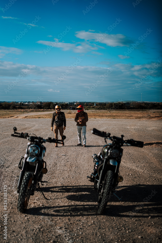 Fototapeta premium three people walk down an empty runway with several motorcycles parked in front of them