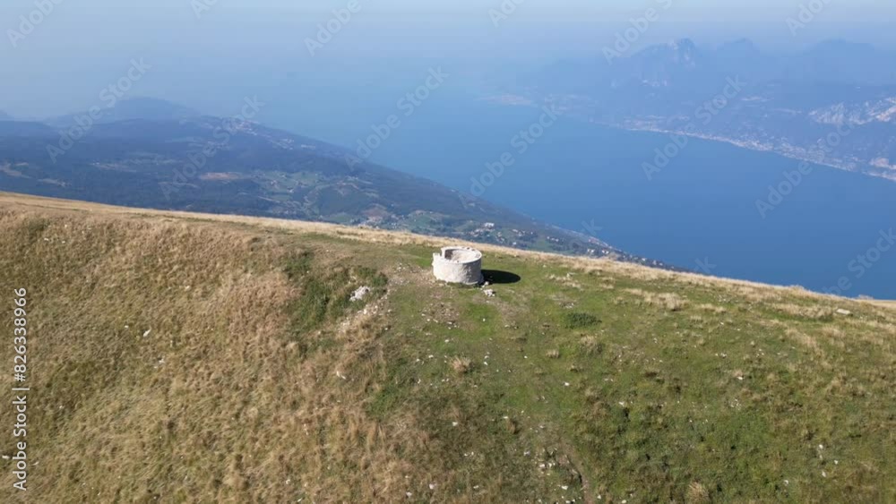 Drone zoom-out shot of Monte Baldo with a lake in the background.