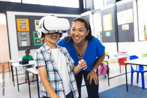 In school, in a classroom, a middle-aged biracial woman and two young boys explore VR