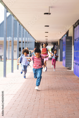 In school, diverse children are running down the hallway with copy space outdoors