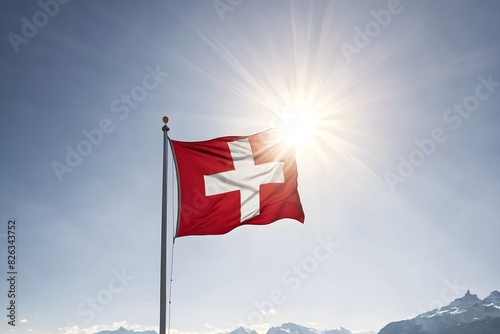 Waving Swiss flag in the wind against background of mountains and blue sky with sunlight. The national flag of Switzerland on the mast. photo