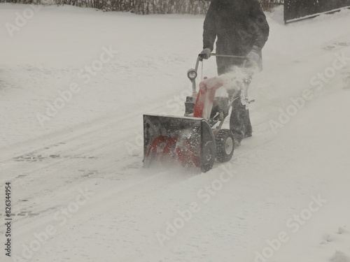 Robotnik clears snow from the sidewalk with a manual snowplow driven by a gasoline engine. Fighting the after-effects of a snowstorm. The power of the winter element