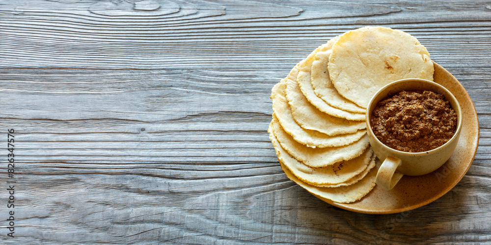 Tortillas made with nixtamalized white corn flour. Veracruz-style thick sauce made with dried chilies, pumpkin seeds, and unhulled sesame seeds. Traditional Mexican meal. Baner with copy space. Tortillas made with nixtamalized white corn flour. Veracruz-style thick sauce made with dried chilies, pumpkin seeds, and unhulled sesame seeds. Traditional Mexican meal. Baner with copy space.