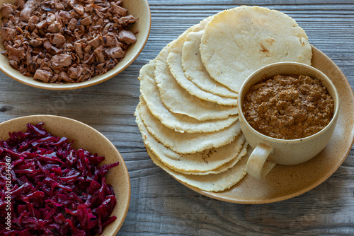 Tortillas made with nixtamalized white corn flour, Veracruz-style thick sauce pipian tlatonile, shredded and roasted jackfruit and red cabbage  sauerkraut. Vegan Mexican-style meal. photo