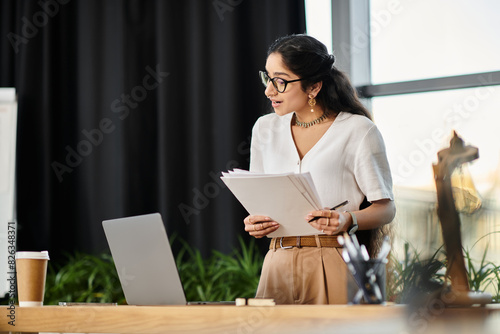 Young indian woman in glasses works diligently at desk with laptop. © LIGHTFIELD STUDIOS
